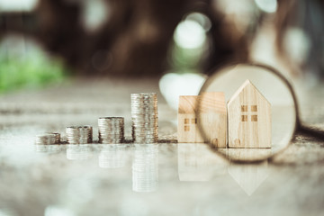 Hand holding magnifying glass and looking at house model, house selection, real estate concept.