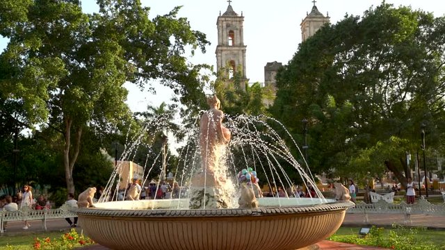 Slow motion with camera moving left with focus on the water fountain in the center of the park in Valladolid, Yucatan, Mexico.