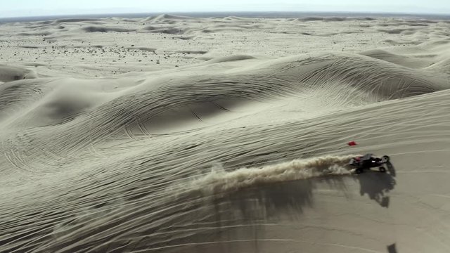 All terrain vehicle ATV driving over sand dunes in desert, aerial view