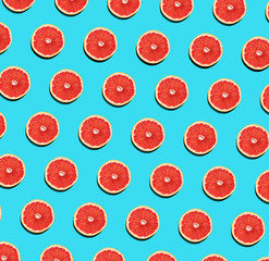 Fruit pattern of fresh grapefruit slices on blue background. Abstract summer fruit background. Flat lay, top view