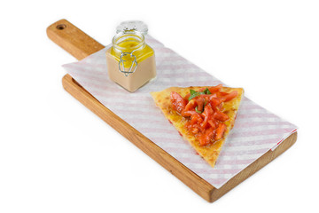 Foccacia with tomatoes and sauce on a cutting board on isolated background