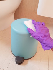 Closeup of lady wearing glove and using sponge to clean bin in toilet. Hygiene concept. 