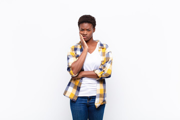 young pretty black womanholding cheek and suffering painful toothache, feeling ill, miserable and...