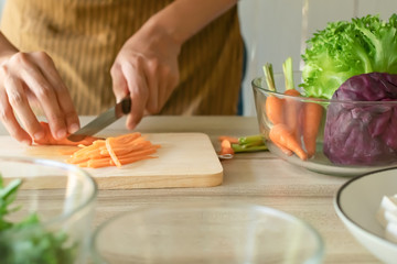 Soft focus Conceptual cooking preparation. People using knives slice the carrots on a wooden. To make healthy vegetable salads, food