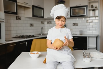 boy in cook hat sitting at a kitchen counter. Little boy in kitchen