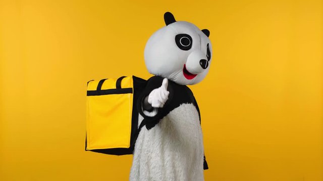 person in panda bear costume with backpack running isolated on yellow