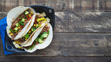 Mexican fajitas in black tray on wooden boards. Copy space. Mexican food concept.