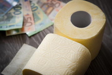 euro bills and toilet paper on wooden background. close-up