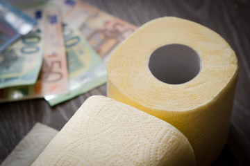 euro bills and toilet paper on wooden background. close-up