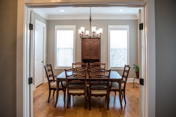 Formal Dining room with a set of wood table and chairs and a chandelier with windows and natural lights and hardwood floors