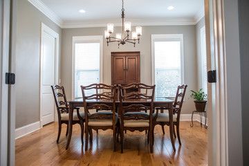 Formal Dining room with a set of wood table and chairs and a chandelier with windows and natural lights and hardwood floors
