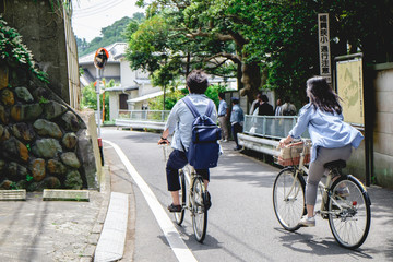 Couple in bikes from back at streets of Kamakura, Japan