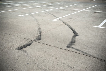 Black tire tracks and white parking lines on the concrete surface