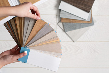 Designer architect holds a palette of textures and decor for a wooden floor made of laminate and vinyl. Interior Design. Planning for repairs and home construction.