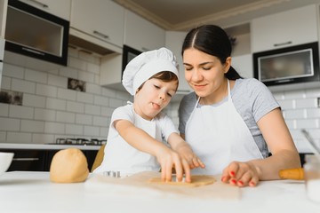 Obraz na płótnie Canvas Happy mother and child in kitchen preparing cookies