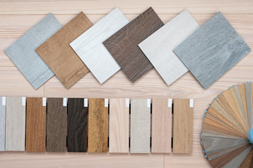 An example of a catalog of luxury vinyl floor tiles and a designer palette with textures with a new interior design for a house or floor on a light wooden background.