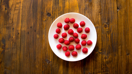 Fresh raspberry in a plate on wooden background