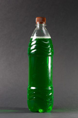 Plastic bottle with a green drink on the background.