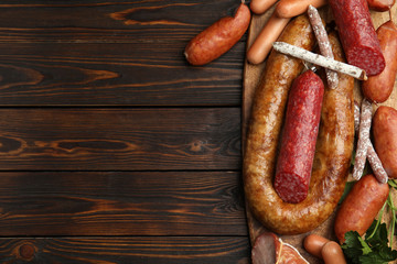 Different tasty sausages on wooden table, top view. Space for text