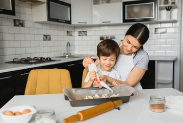 Happy mother and child in kitchen preparing cookies