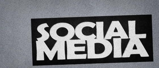 Social media sign, white text on gray asphalt background
