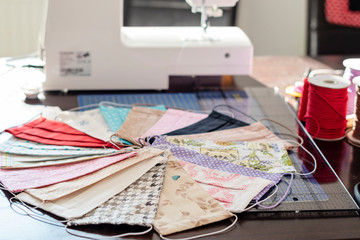 Selective focus on handmade cotton fabric cotton face mask on mat with sewing accessories. Protection against saliva, cough, dust, pollution, virus, bacteria, COVID-19.