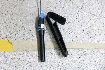 Closeup hand holding fiber optic cables with visual fault locator laser in the networking...