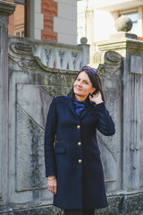 Nice, brunette woman wearing in black coat walking in old city. Smile, cute girl in Batumi, Georgia. Spring time.