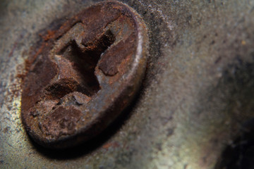 Macro shots an old, dusty and rusty screw on the door handles mechanism