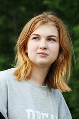 A thoughtful young girl sitting outside in summer