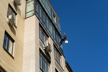 Industrial climbing. Climber wash windows in a high-rise building. Cleaning of windows glass elements.