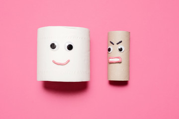 Happy smiling full toilet paper roll next to an angry empty toilet paper roll looking at it with...