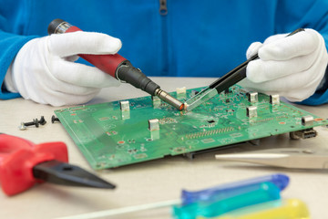 El técnico electrónico reemplaza un conector en la placa de circuito