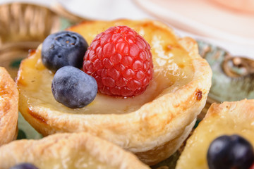 Puff pastry tartlet stuffed with creme brulee and fresh blueberries and raspberries, close up