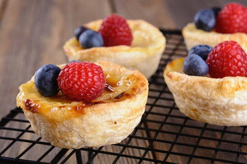 Small puff pastry tartlets stuffed with creme brulee and fresh blueberries and raspberries