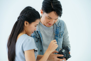 young handsome attractive man photographer displayed picture in  camera after  taking photo of beautiful model young asian woman in studio during COVID-19 pandemic working at home quarantine