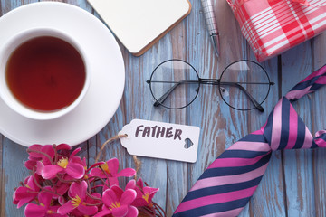 Happy Father's Day inscription with tie and watch on wooden background