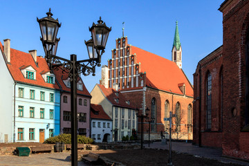 Old town square with beautiful St. John's Church and cute red roofed houses in Riga, Latvia