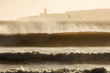 Big waves of ocean in Essaouira with Mosque in background. Morocco
