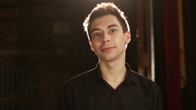 Handsome man looking at camera and smiling against backlight background