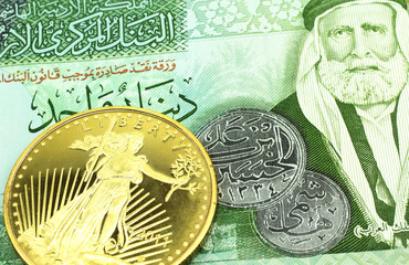 A macro image of a green one dinar note from Jordan with a gold coin.  Shot close up.
