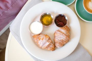 breakfast with cups of coffee with cream and croissants on wooden table