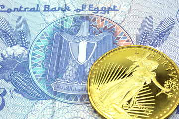 A macro image of a blue twenty five piastre note from Egypt with a gold coin.  Shot close up.