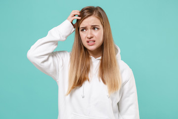 Preoccupied young woman girl in casual white hoodie posing isolated on blue turquoise background studio portrait. People emotions lifestyle concept. Mock up copy space. Put hand on head looking aside.