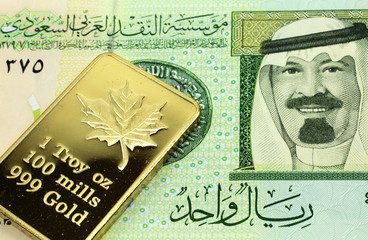 A macro image of a green one Saudi riyal bank note with a gold bar.  Shot close up.