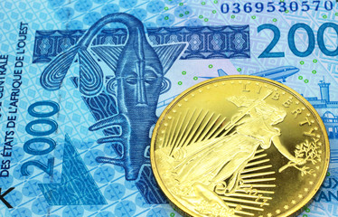 A macro image of a blue two thousand West African franc note with a gold coin.  Shot close up.