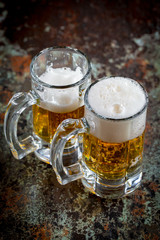 Light frothing beer in a glass, on an old background.