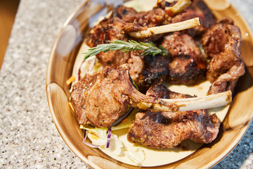 Mutton ribs with a branch of a thyme are fried on a grill, a smoke, firewood, steam, close up