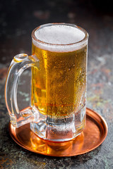 Light frothing beer in a glass, on an old background.