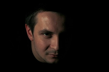 Portrait of a young man in dark key. Guy's portrait on black background. Concept of man's emotions.